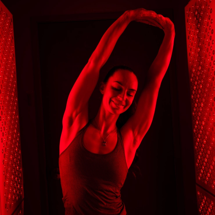 Woman with her hands above her head smiling and enjoying red light therapy